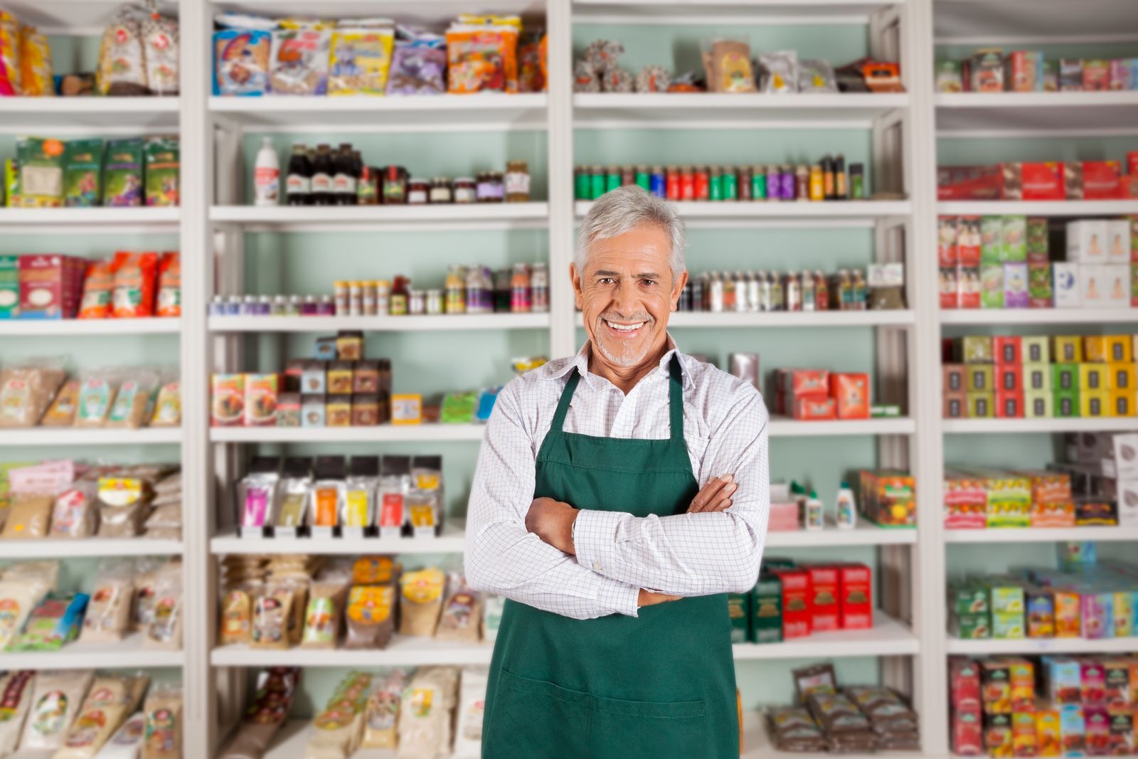A business owner standing in front of stocked store shelves